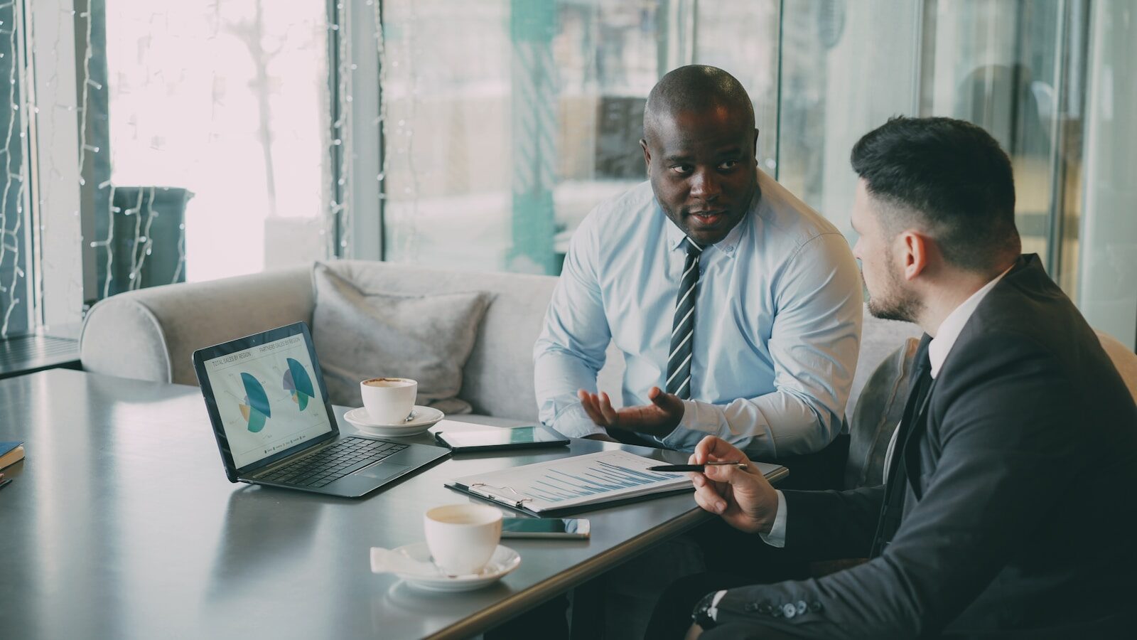 Two businessmen discussing charts on a laptop